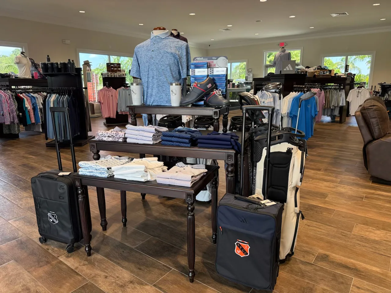 Pro shop interior with folded apparel on display tables, mannequin wearing blue polo, luggage, and clothing racks at St. Petersburg country club.